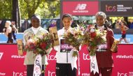 Ethiopia's Yalemzerf Yehualaw celebrates on the podium after winning the women's elite race of the London Marathon alongside second place Kenya's Joyciline Jepkosgei and third place Ethiopia's Alemu Megertu in London on October 2, 2022.   Action Images via Reuters/Andrew Boyers