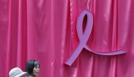 Visitors walk past a sculpture of a pink ribbon installed to promote the 