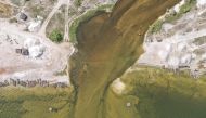 This aerial view shows the breach where flood waters broke through and water from the surrounding flooded towns is pumped into Lake Rose (also known as Lake Retba) in Niaga on October 19, 2022. (Photo by JOHN WESSELS / AFP)