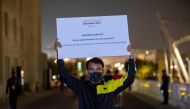 An educational volunteer holding up a sign outside Education City stadium during the FIFA Arab World Cup. 