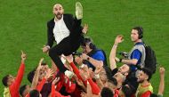 Morocco’s players throw coach Walid Regragui in the air as they celebrate after defeating Spain on Tuesday. AFP