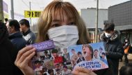 A fan holds pictures of BTS singer Jin in front of a military training unit in Yeoncheon on December 13, 2022, as the place where BTS singer Jin is scheduled to arrive to begin his military service. Photo by Jung Yeon-je / AFP