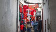 People walk past a sports apparel shop in Morocco's capital Rabat on December 13, 2022 a day ahead of the Qatar 2022 FIFA World Cup semi-final football match between Morocco and France. (Photo by FADEL SENNA / AFP)