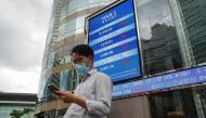 People walk past a screen displaying the Hang Seng stock index outside Hong Kong Exchanges, in Hong Kong, China July 19, 2022. Reuters/Lam Yik
