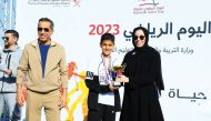 Minister of Education and Higher Education H E Buthaina bint Ali Al Jabr Al Nuaimi awards a student at a sport competition held as part of the ministry's National Sport Day activities. Undersecretary of the Ministry of Education and Higher Education Dr. Ibrahim bin Saleh Al Nuaimi is also seen.