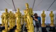 A worker lines up Oscar statues, as preparations are underway for the 95th Oscars Academy Awards, in Hollywood, California, on March 9, 2023. (Photo by ANGELA WEISS / AFP)