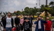 People watch a partial solar eclipse in Surabaya on April 20, 2023. (Photo by Juni Kriswanto / AFP)