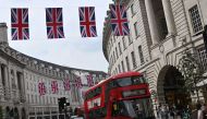 A red London bus passes beneath Union flags on Regent Street, in central London, on April 30, 2023 ahead of the coronation ceremony of Charles III and his wife, Camilla. (Photo by Justin Tallis / AFP)