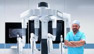 Surgeon Dr. Salaam Sadi standing next to the Da Vinci Xi® robotic surgery equipment