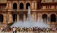 A group of schoolchildren on a excursion cool off walking along a fountain at the Plaza Espana square in Seville on April 26, 2023 as Spain is bracing for an early heat wave. (Photo by CRISTINA QUICLER / AFP)