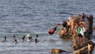 A Libyan dives into the water in Tripoli on July 6, 2023, during a heatwave. (Photo by Mahmud Turkia / AFP)