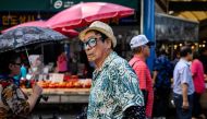 :A man wearing a hat and sunglasses walks along a street during a hot day in Seoul on August 4, 2023. (Photo by ANTHONY WALLACE / AFP)
