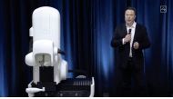 This video grab made from the online Neuralink livestream shows Elon Musk standing next to the surgical robot during his Neuralink presentation on August 28, 2020.(Photo by Neuralink / AFP) 

