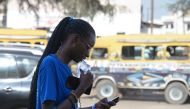 A woman drinks from a plastic sachets filled with drinkable water in Dakar, on August 25, 2023. Photo by SEYLLOU / AFP