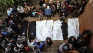 People stand over the shrouded bodies of loved ones killed during Israeli bombardment at Nasser Hospital in Khan Yunis on the southern Gaza Strip on December 27, 2023. Photo by AFP