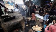 Palestinian women make break in ovens at a makeshift camp housing displaced Palestinians, in Rafah in the southern Gaza Strip on January 2, 2024. Photo by AFP
