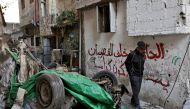 A man walks next to a destroyed car following an overnight Israeli raid on the Tulkarm refugee camp in the occupied West Bank, on January 9, 2024. Photo by Zain JAAFAR / AFP