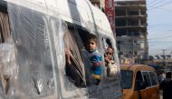 Palestinians look from the windows of a minibus at a market in Rafah refugee camp in the Gaza Strip on January 8, 2024. Photo by AFP