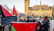 A protestor holds a Palestinian flag during a demonstration simultaneously at the hearing at the International Court of Justice (ICJ) in The Hague, January 11, 2024. Photo by Robin Utrecht / ANP / AFP