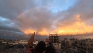 A picture taken from Rafah shows children pointing towards a rainbow over the southern Gaza Strip on January 11, 2024. Photo by AFP