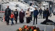 People walk past destroyed buildings in Rafah on the southern Gaza Strip on January 14, 2024. Photo by AFP