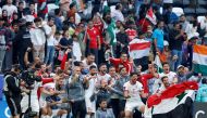 Syria's players celebrate with a national flag on the pitch after the Qatar 2023 AFC Asian Cup Group B football match between Syria and India at Al-Bayt Stadium in al-Khor, north of Doha, on January 23, 2024. (Photo by KARIM JAAFAR / AFP)