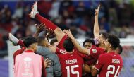 Qatar’s players toss their captain Hassan Al Haydos in the air. AFP