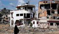 A woman walks past a destroyed building in the Maghazi camp for Palestinian refugees, which was severely damaged by Israeli bombardment. Photo by ANAS BABA / AFP