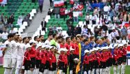 Japan's players (in blue) and Iran's players (in white) stand for their national anthems before the start of the Qatar 2023 AFC Asian Cup quarter-final football match at Education City Stadium. (Photo by Hector Retamal / AFP)