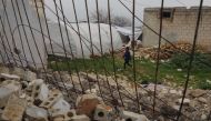 A child walks past a destroyed house at a camp for quake-displaced Syrians in Jindayris town in the northwest of Aleppo province on February 3, 2024. (Photo by Aaref Watad / AFP)