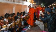 (Files) Buddhist monks line up at dawn to receive food and alms from devotees in front of a pagoda in Luang Prabang on January 28, 2024. (Photo by Tang Chhin Sothy / AFP)