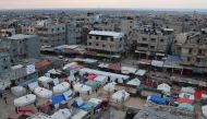 Displaced Palestinians stand outside their tents in Rafah in the southern Gaza Strip on February 14, 2024. Photo by SAID KHATIB / AFP