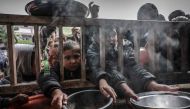 Displaced Palestinian children gather to receive food at a government school in Rafah in the southern Gaza Strip on February 19, 2024. (Photo by Mohammed Abed / AFP)