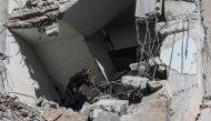 A Palestinian woman searches amid the rubble of a residential building hit in an overnight Israeli air strike in Rafah in the southern Gaza Strip on March 9, 2023. (Photo by Said Khatib / AFP)
