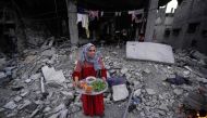 A Palestinian woman prepares to serve an iftar meal, the breaking of fast, amidst the ruins of her family's house, on the first day of the Muslim holy fasting month of Ramadan, in Deir el-Balah in the central Gaza Strip on March 11, 2024, amid ongoing battles between Israel and the Palestinian group Hamas. (Photo by AFP)
