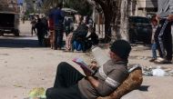 A Palestinian man sits reading in a street in Rafah in the southern Gaza Strip on March 15, 2024, amid ongoing battles between Israel and the militant group Hamas. (Photo by MOHAMMED ABED / AFP)
