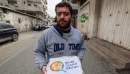 A man carries food aid packages provided by the non-profit non-governmental organisation World Central Kitchen, in Rafah in the southern Gaza Strip on March 17, 2024, amid the ongoing conflict between Israel and the militant group Hamas. (Photo by MOHAMMED ABED / AFP)
