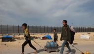 Palestinian children transport water to a camp for displaced people in Rafah in the southern Gaza Strip on March 17, 2024, amid ongoing battles between Israel and the militant group Hamas. (Photo by Mohammed Abed / AFP)