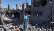 A Palestinian man picks a blue dress from the rubble following overnight Israeli bombardment which hit the al-Habash family home at the Nuseirat refugee camp in the central gaza Strip on March 20, 2024. (Photo by AFP)
