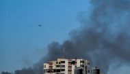 Smoke rises above the Rimal district in gaza City as a military aircraft prepares to airdrop humanitarian aid on March 20, 2024. (Photo by AFP)