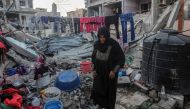 :A woman hangs laundry amidst the rubble of the Rabaya home, which was destroyed by an Israeli strike, during the Muslim holy month of Ramadan in Rafah on March 23, 2024. (Photo by SAID KHATIB / AFP)
