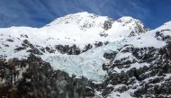 A glacier sits between mountains covered in snow in the Mount Aspiring National Park located near Queenstown on the South Island of New Zealand on October 20, 2023. Photo by David GRAY / AFP