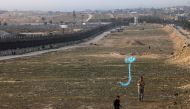 A displaced Palestinian child flies a kite near the border with Egypt in Rafah in the southern Gaza Strip on March 29, 2024. (Photo by SAID KHATIB / AFP)
