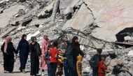 Palestinian women and children walk near a building destroyed in Israeli bombardment in Rafah in the southern Gaza Strip on March 31, 2024. (Photo by MOHAMMED ABED / AFP)
