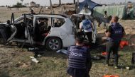 United Nations staff members inspect the carcass of a car used by US-based aid group World Central Kitchen, that was hit by an Israeli strike the previous day in Deir al-Balah in the central Gaza Strip on April 2, 2024. (Photo by AFP)