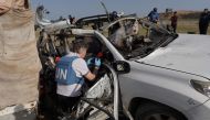 United Nations staff members inspect the carcass of a car used by US-based aid group World Central Kitchen, that was hit by an Israeli strike the previous day in Deir al-Balah in the central Gaza Strip on April 2, 2024. Photo by AFP.