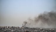 This picture taken from Israel's southern border with the Gaza Strip shows smoke billowing behind destroyed buildings due to Israeli strikes on the besieged Palestinian territory on April 2, 2024. (Photo by RONALDO SCHEMIDT / AFP)
