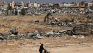 A Palestinian elderly woman pushes a wheelchair past rubble in Khan Yunis on April 7, 2024. (Photo by AFP)
