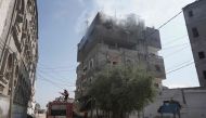 A firefighter truck deploys as smoke billows from a building following Israeli bombardment in Nuseirat, central Gaza, on April 12, 2024. (Photo by AFP)