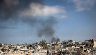 Smoke billows as a man walks amid the rubble of buildings destroyed during Israeli bombardment in Khan Yunis, on the southern Gaza Strip on April 16, 2024. (Photo by AFP)
